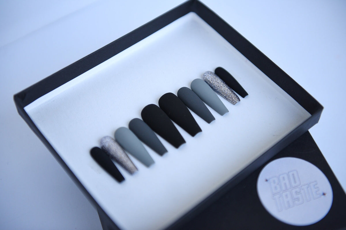 Black and grey matte press-on nails with silver glitter accents – detail view