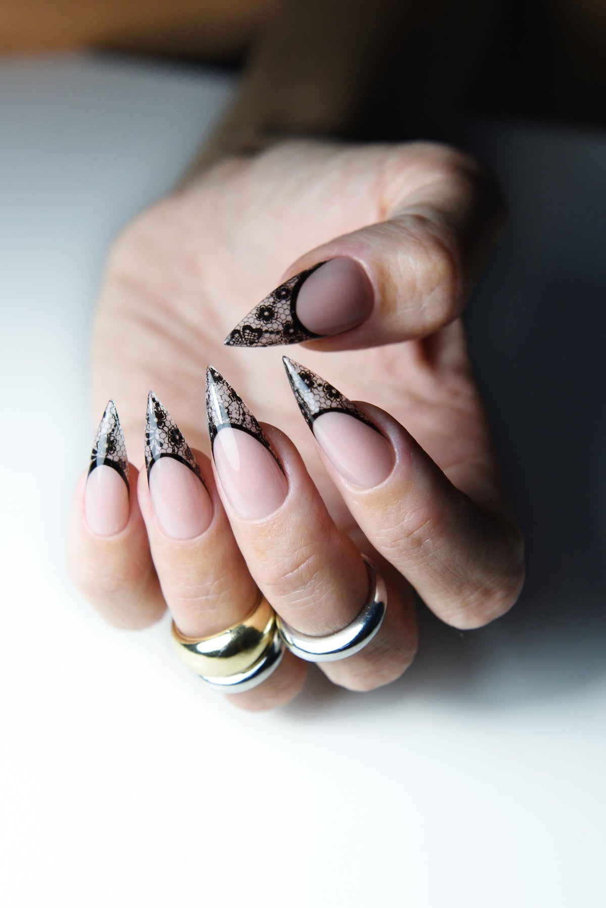 Nude pink press-on nails with pointed black lace French tips – detail view