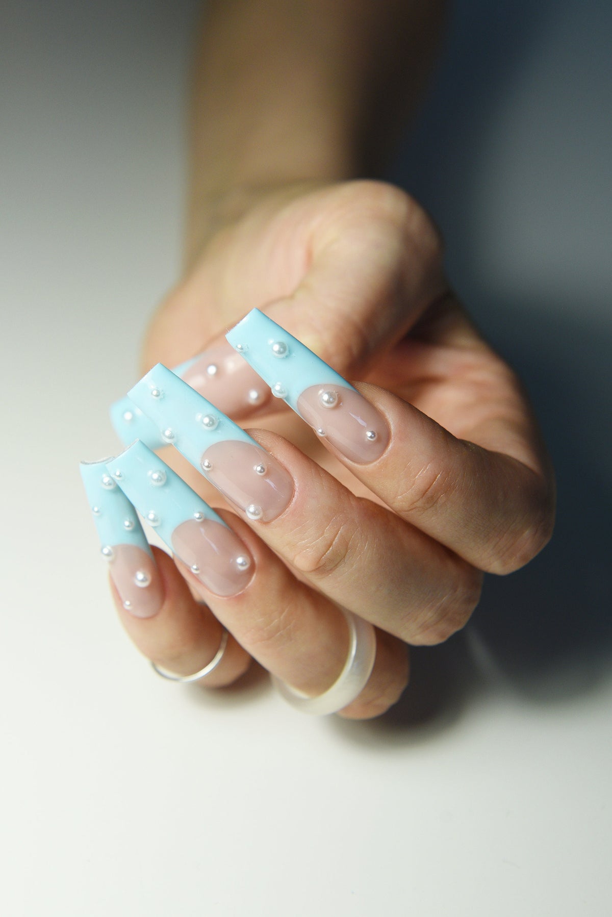 Pastel blue French press-on nails with pearl accents, front angle