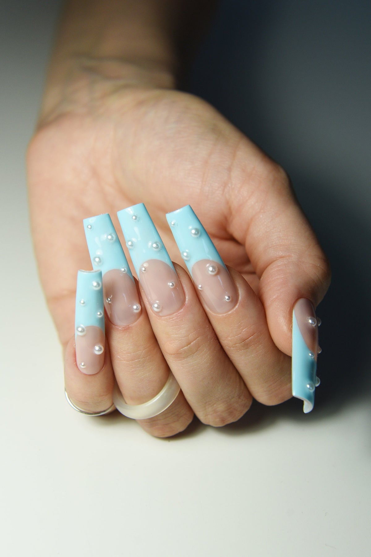 Pastel blue French press-on nails with pearls, glossy close-up