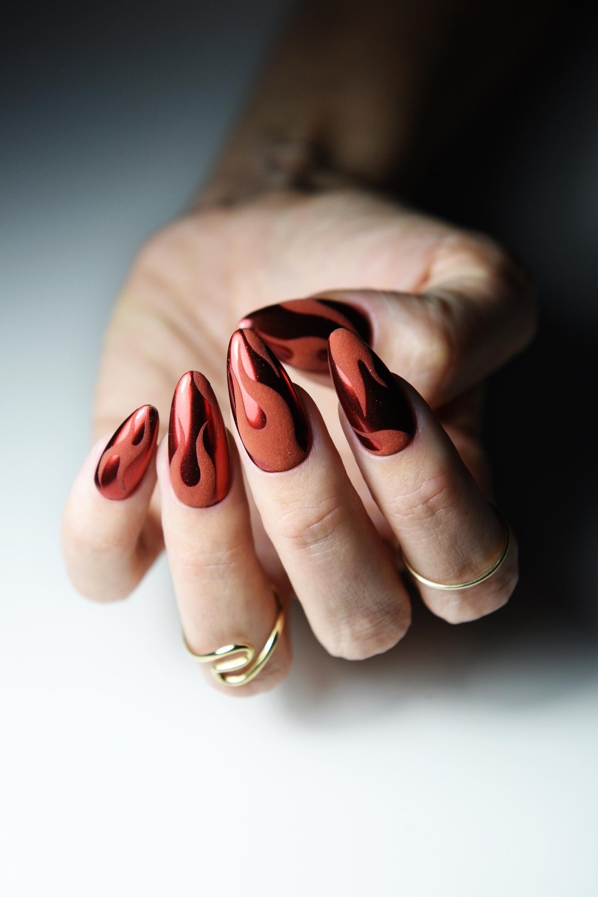 Warm red chrome press-on nails with matte black flame design