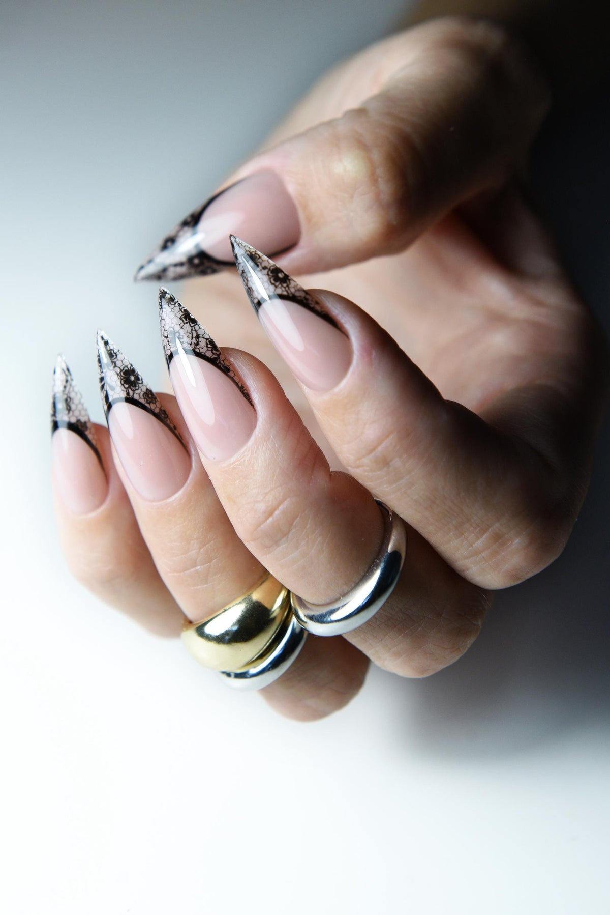 Nude pink press-on nails with pointed black lace French tips – detail view