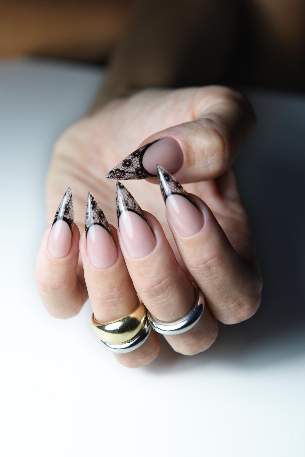 Nude pink press-on nails with pointed black lace French tips – detail view