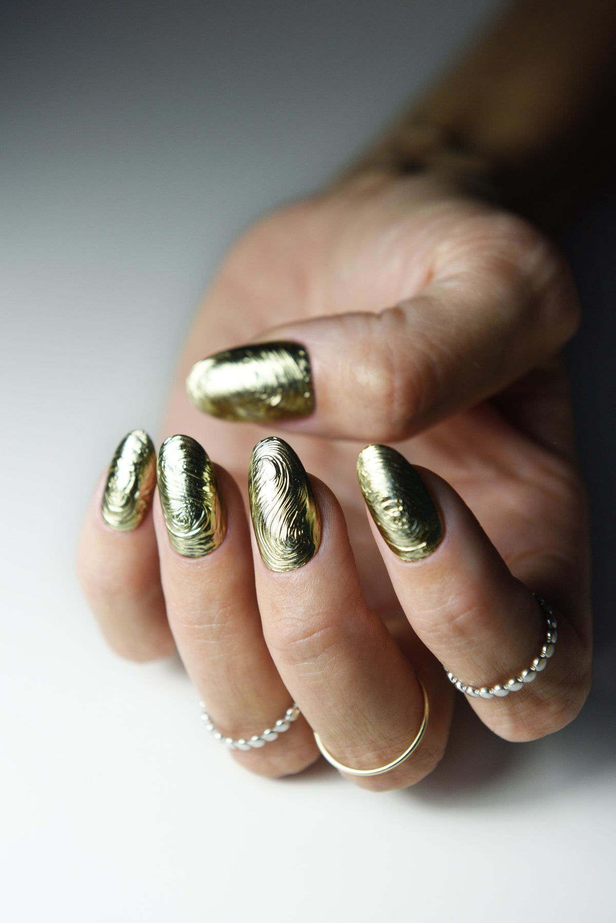 Sculpted gold chrome swirl press-on nails with liquid-metal texture – detail view