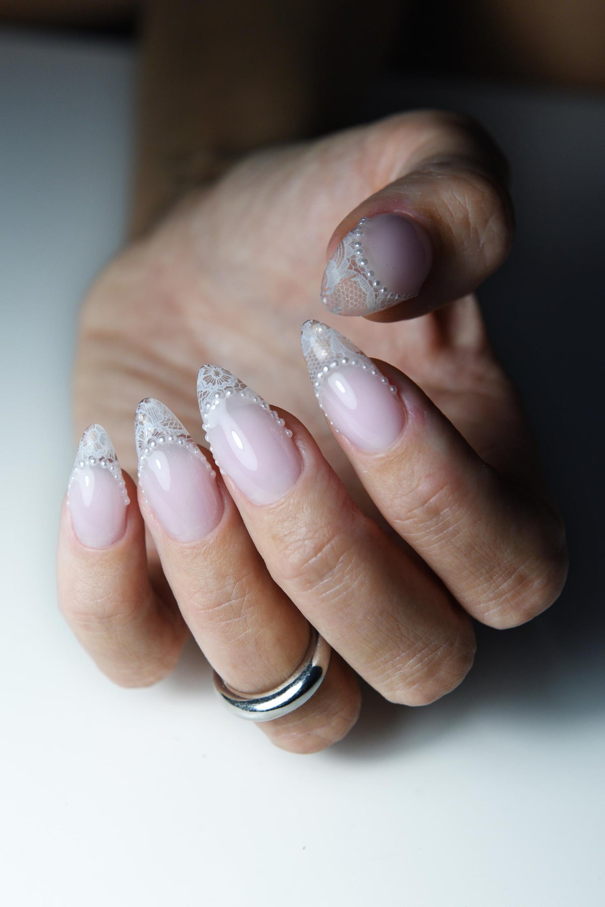 Blush pink press-on nails with white lace French tips and tiny pearls – detail view