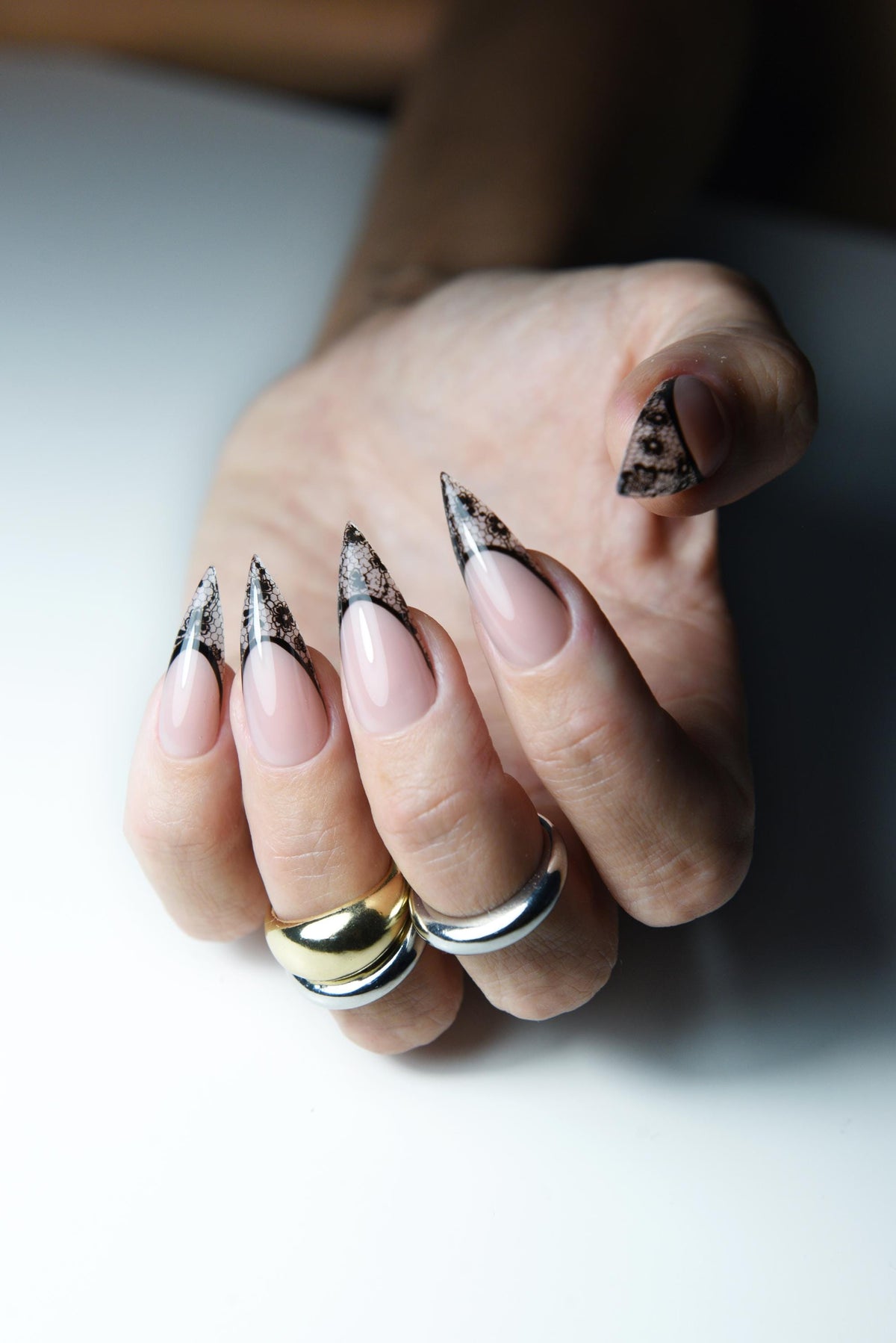 Nude pink press-on nails with pointed black lace French tips – detail view