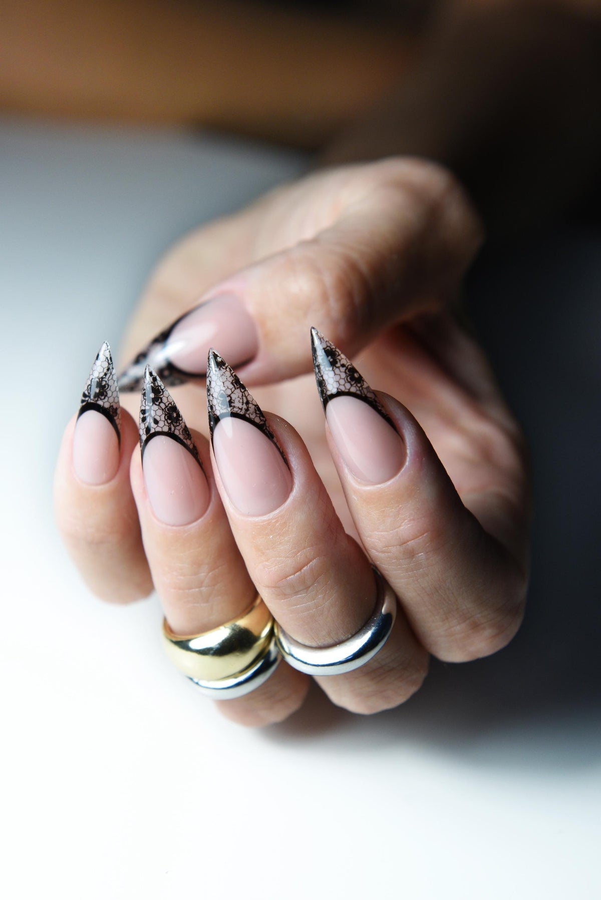 Nude pink press-on nails with pointed black lace French tips