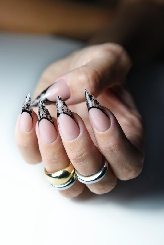 Nude pink press-on nails with pointed black lace French tips