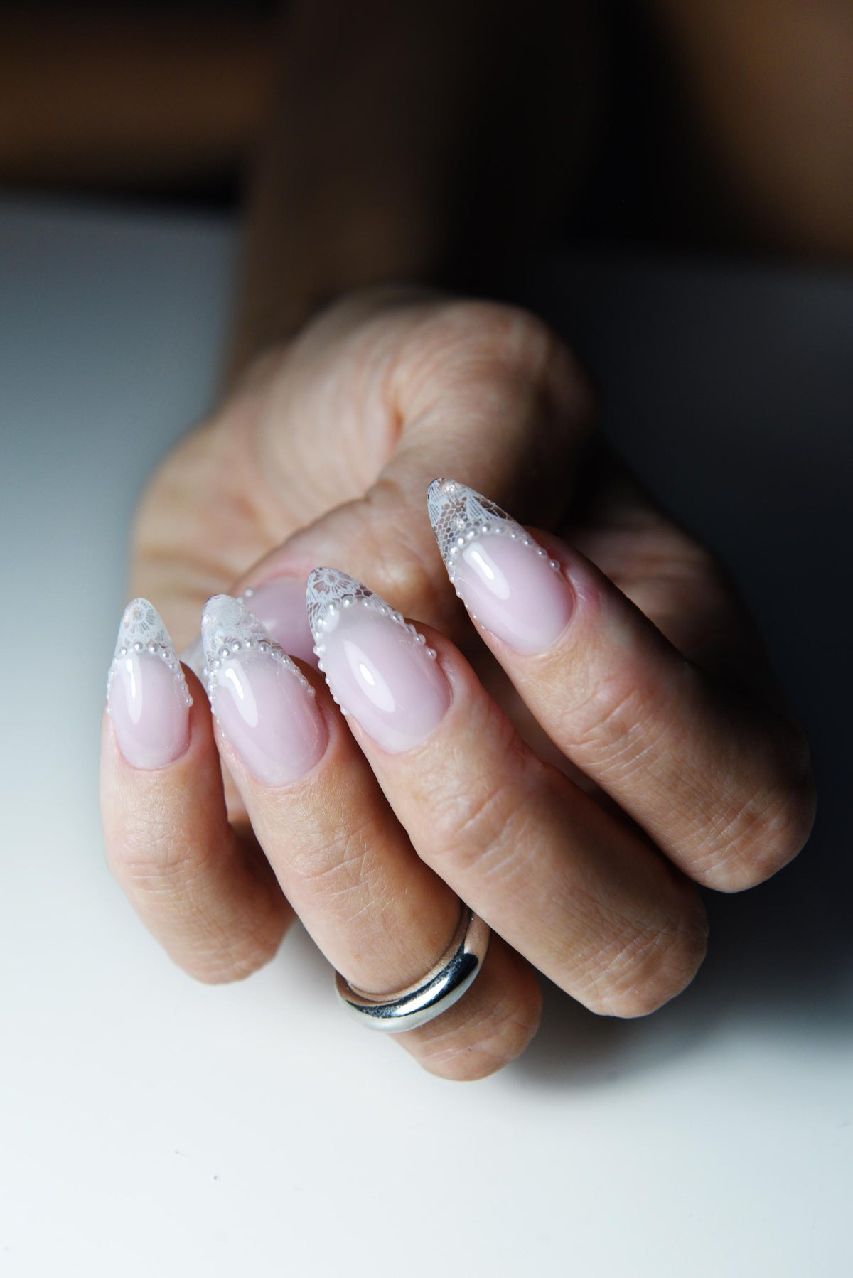 Blush pink press-on nails with white lace French tips and tiny pearls – detail view