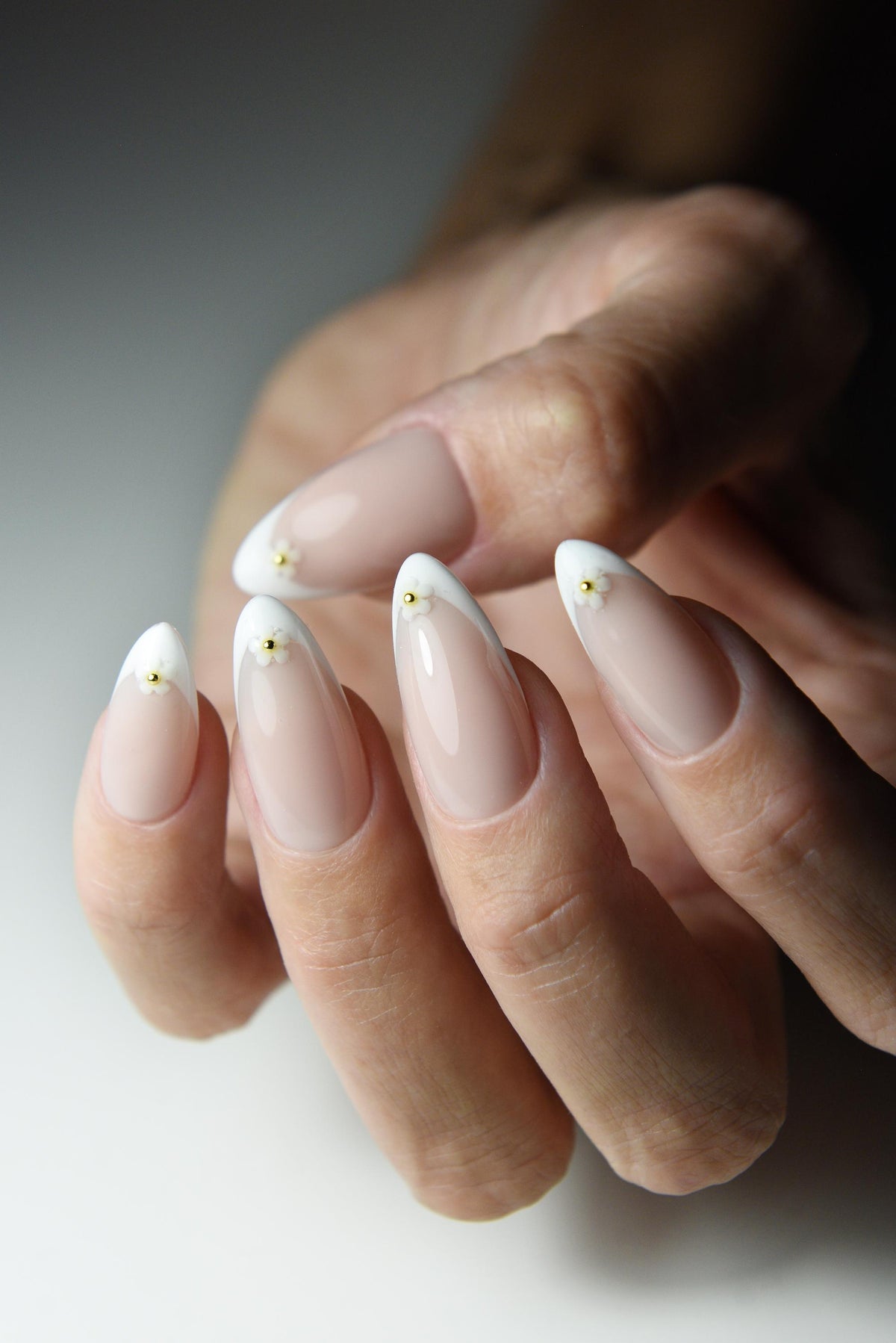 White French tip press-on nails with tiny daisies on every nail